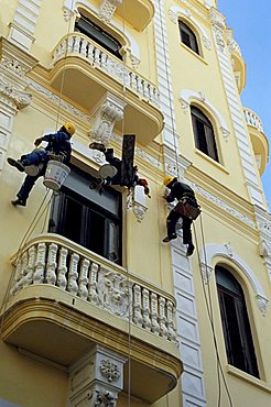 Men painting building without aid of scaffolding, Havana, Cuba, West Indies, Central America