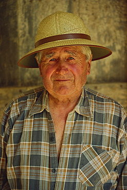 Head and shoulders portrait of a French farmer in a straw hat looking at the camera, in the Midi-Pyrenees, France, Europe