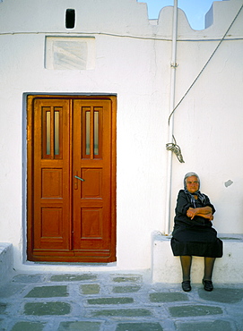 Old lady sitting by church, Mykonos (Mikonos), Cyclades Islands, Greek Islands, Greece, Europe