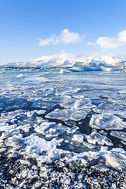 Mountains behind the frozen water of Jokulsarlon Iceberg Lagoon, Jokulsarlon, south east Iceland, Polar Regions