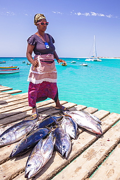 Colourful local woman selling freshly caught yellow fin tuna fish from the pier at Santa Maria, Sal island, Cape Verde, Africa