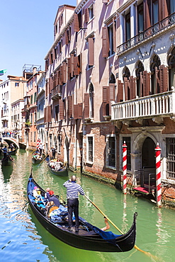 Gondolier, rowing a gondola, with tourists, along canal, in front of a palazzo, Venice, UNESCO World Heritage Site, Veneto, Italy, Europe