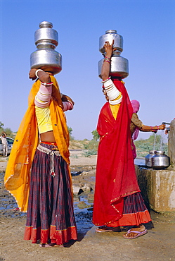 Two women by a well carrying water pots, Barmer, Rajasthan, India 