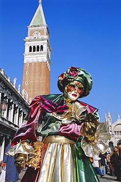 Person wearing masked carnival costume, St. Mark's Square and Campanile behind, Venice Carnival, Venice, Veneto, Italy
