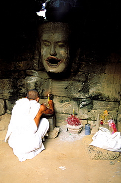 Monk makes an offering, Neak Pean temple, Angkor, Cambodia, Asia