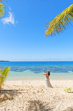 Woman taking photographs on a tropical beach, Drawaqa Island, Yasawa islands, Fiji, South Pacific Islands, Pacific