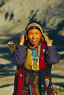 Gurung woman carrying goods in a woven basket (doto) on her back, near MUKtinath, Nepal