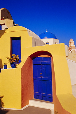 Blue and yellow traditional house with churches in the background, Oia village, Oia, Santorini (Thira), Cyclades Islands, Greece