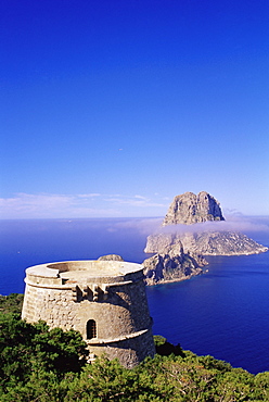 View of a defence tower and rocky islet of Es Vedra, surrounded by mist, near Sant Antoni, Ibiza, Balearic Islands, Spain, Mediterranean, Europe