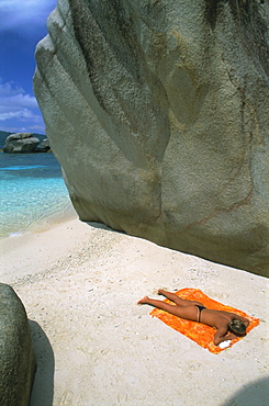 Woman sunbathing on beach beween rocks, Coco Island, Praslin, Seychelles, Indian Ocean, Africa