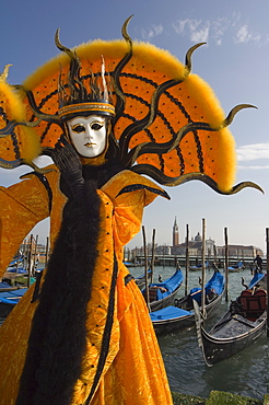 Masked face and costume at the Venice Carnival, with gondolas on waterfront and San Giorgio Maggiore behind, Venice, Veneto, Italy, Europe