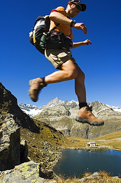 Hiker running on trail above lake at Schwarzee Paradise, Zermatt Alpine Resort, Valais, Switzerland, Europe