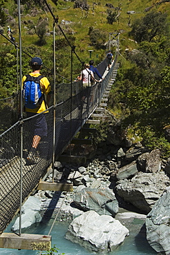 Hikers crossing a suspension bridge on Rob Roy Glacier Hiking Track, Mount Aspiring National Park, Otago, South Island, New Zealand, Pacific