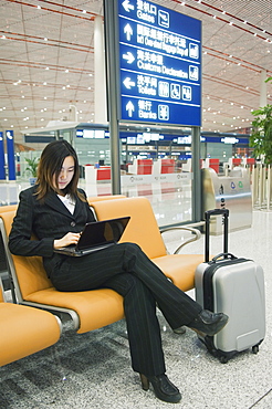 A Chinese business woman using a laptop computer at Beijing Capital Airport, part of new Terminal 3 building opened February 2008, second largest building in the world, Beijing, China, Asia