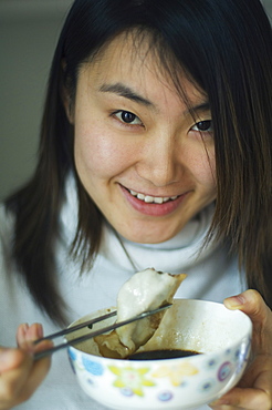 A Chinese girl eating dumplings, which are eaten traditionally on the Eve of Chinese New Year, China, Asia