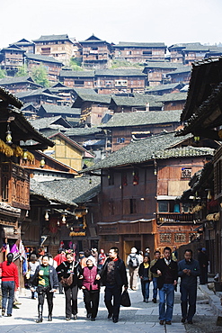 Tourists walking by wooden houses on the old streets of Xijiang, Guizhou Province, China, Asia