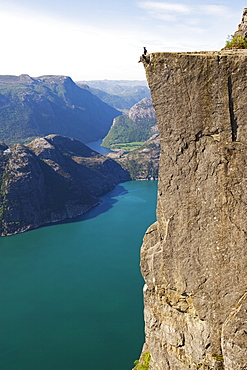 Man sitting on Preikestolen (Pulpit Rock) above fjord, Lysefjord, Norway, Scandinavia, Europe