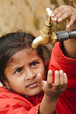 Young girl checking to see if the communal village water tap has water, as it runs dry daily, Pokhara, Nepal, Asia