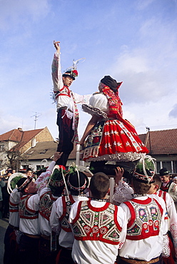 Maiden and lad standing on chairs held by other lads to cheer their union, in traditional dress, St. Martin Feast with Wreath Festival, Svatoborice-Mistrin, Brnensko, Czech Republic, Europe