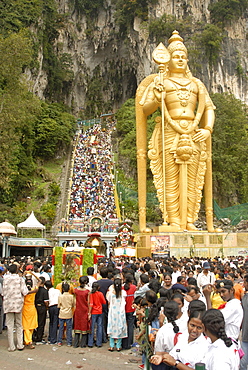 Statue of Hindu deity with pilgrims walking 272 steps up to Batu Caves during Hindu Thaipusam Festival, Sri Subramaniyar Swami Temple, Batu Caves, Selangor, Malaysia, Southeast Asia, Asia