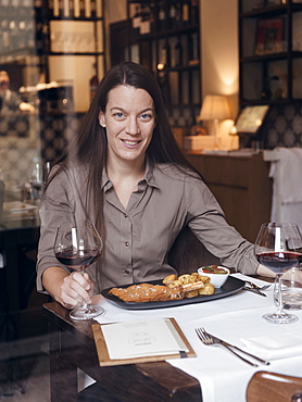 Portrait of the owner of the Restaurant Brunello in Milano along with one of their traditional dishes: Cotoletta Milanese served with baked french potatoes and a tomatoes salad with a glass of red wine