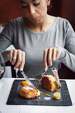 Portrait of a young lady eating Cotoletta Milanese cooked by Restaurant Trattoria del Nuovo Macello served with a puree of carrots and cardamom and a fennel chutney on a plate of cast iron Milan, Lombardy; Italy, Europe