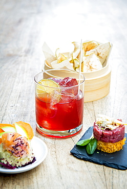 Still life of Giulietta cocktail with apple chips, steak tartare on a toast, foie gras, mango, wasabi sesame and chickpeas hummus, smoked salmon, beetroot powder, green apple. Rita Bar, Milan, Lombardy, Italy, Europe