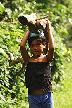 Young girl carries a log balanced on her head inside the Cerro Verde park. El Salvador, Central America.