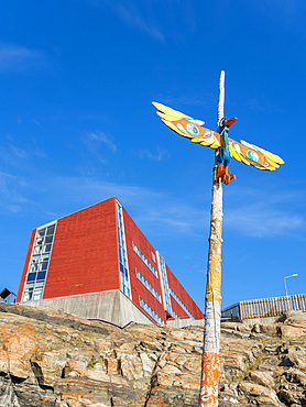 Mythical bird on pole and school in the background. Small town Uummannaq in the north of west greenland. America, North America, Greenland, Denmark