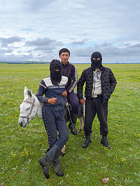 Young shepherds on their summer pasture. the face mask is protecting the faces from cold, sun and dust. Alaj Valley in front of the Trans-Alay mountain range in the Pamir mountains. Asia, central Asia, Kyrgyzstan