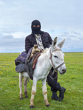 Young shepherds on their summer pasture. the face mask is protecting the faces from cold, sun and dust. Alaj Valley in front of the Trans-Alay mountain range in the Pamir mountains. Asia, central Asia, Kyrgyzstan