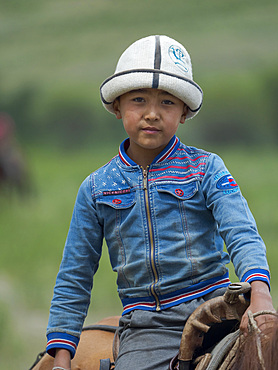 Child on horseback. Folk Festival commemorating the origin myth the Tien Shan Maral (Tian Shan wapiti), an origin myth of the Kyrgyz tribes. Near Tasch Baschat, Naryn region. Asia, Central Aisa, Kyrgyzstan