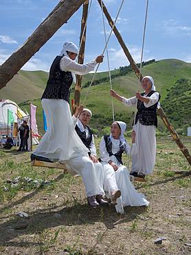 Woman in traditional garb having fun on a swing. Folk Festival commemorating the origin myth the Tien Shan Maral (Tian Shan wapiti), an origin myth of the Kyrgyz tribes. Near Tasch Baschat, Naryn region. Asia, Central Aisa, Kyrgyzstan