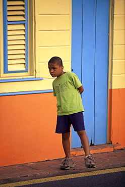 Young boy standing by a colourful house in Trois Ilets, Martinique, Lesser Antilles, West Indies, Caribbean, Central America