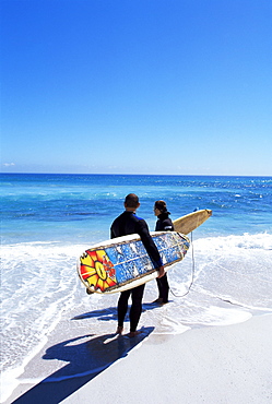 Two surfers walking with their boards on Kommetjie beach, Cape Town, South Africa, Africa