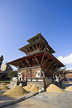 Piles of grain in front of the triple roofed pagoda of the Rato Machendranath temple, Patan, Kathmandu, Nepal, Asia