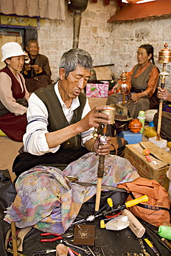 Carrying out routine maintenance of prayer wheels on a monastery roof, Lhasa, Tibet, China, Asia