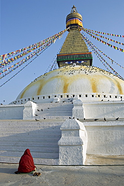 Monk in meditative prayer before the Buddha eyes of Boudha, the Tibetan Buddhist stupa at Bodhnath, UNESCO World Heritage Site, Kathmandu, Nepal, Asia