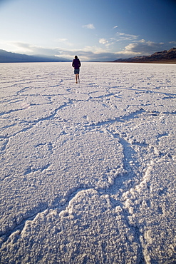 Woman walking on salt flats, Badwater Basin, at minus 282 feet the lowest point in the United States, Death Valley National Park, California, United States of America, North America