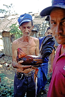 A farmer holding a fighting-cock at a cockfight in rural Pinar del Rio Province in western Cuba, Cuba