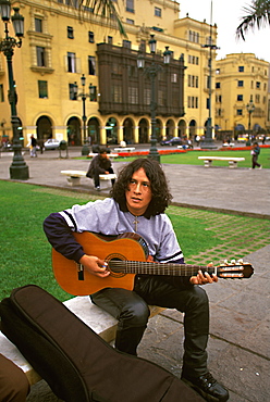 Student musician playing the guitar and performing in the Plaza de Armas, Lima, Peru