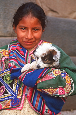 Ancient capital of the Incas portrait of a young Quechua Indian girl in traditional dress with a puppy carried in her shawl, Cuzco, Highlands, Peru