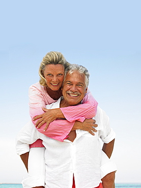 senior couple on beach hugging