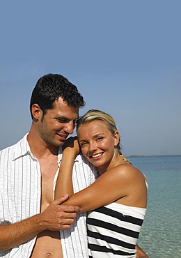 Couple embracing on beach, smiling