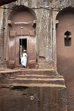 A priest stands at the entrance to the rock-hewn church of Bet Gabriel-Rufael, in Lalibela, UNESCO World Heritage Site, Ethiopia, Africa