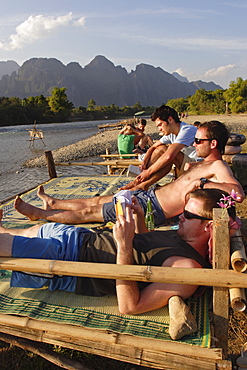 Backpackers relax by the Nam Song river in Vang Vieng, Laos, Indochina, Southeast Asia, Asia