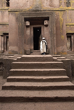 A priest stands at the entrance to the rock-hewn church of Bet Giyorgis (St. George), in Lalibela, UNESCO World Heritage Site, Ethiopia, Africa