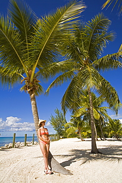 Woman leaning against palm tree, Princess Cays, Eleuthera Island, Bahamas, Greater Antilles, West Indies, Caribbean, Central America