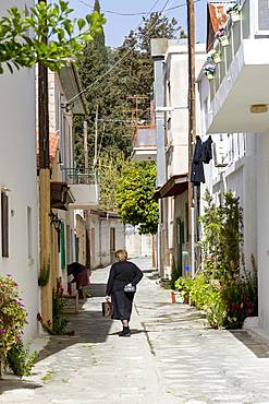 Lady in traditional dress walking in a quiet street in the historic village of Omodos in the Troodos mountains, Cyprus, Europe