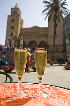 Prosecco wine on cafe table, cathedral behind, Piazza Duomo, Cefalu, Sicily, Italy, Europe